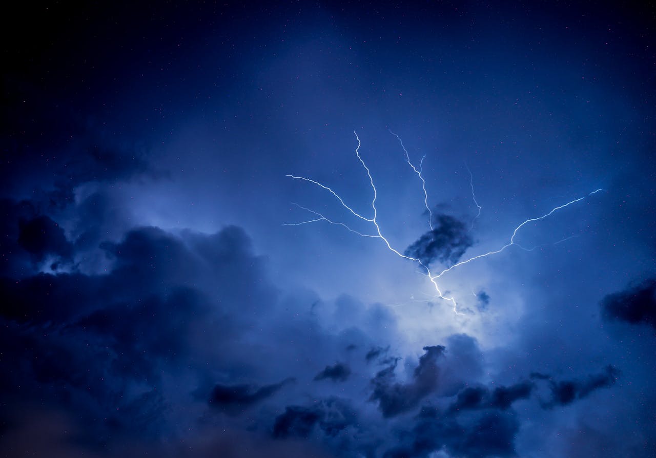 Dramatic lightning strike illuminating a dark, overcast night sky.